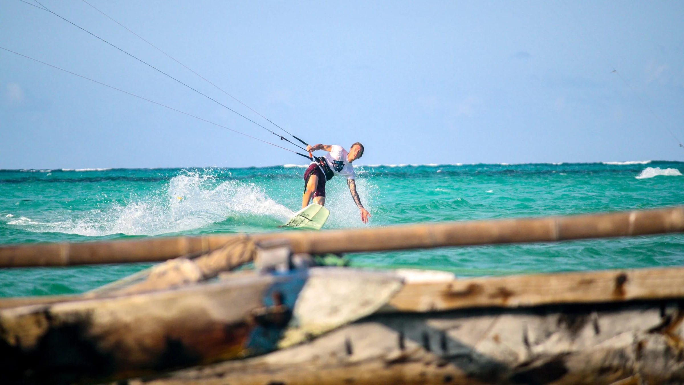 Kitesurfer op turquoise water, gezien vanaf een houten boot