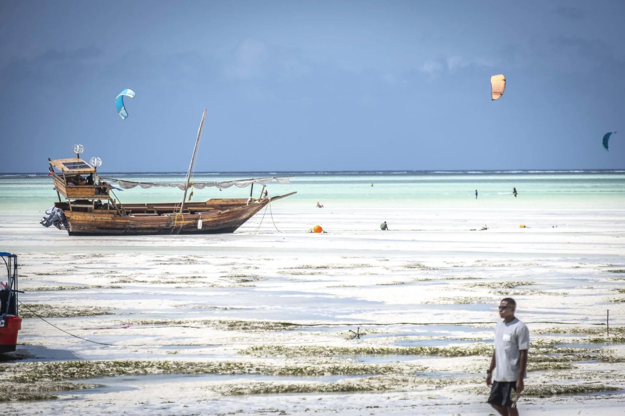 Turquoise lagune bij Paje met kites en een houten boot op de voorgrond