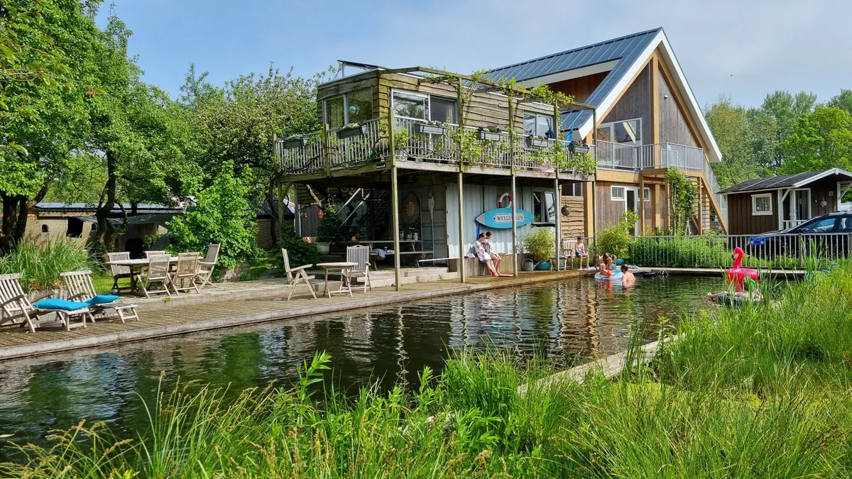 Natuurlijke zwemvijver bij het houten gebouw van Camping Welgelegen.